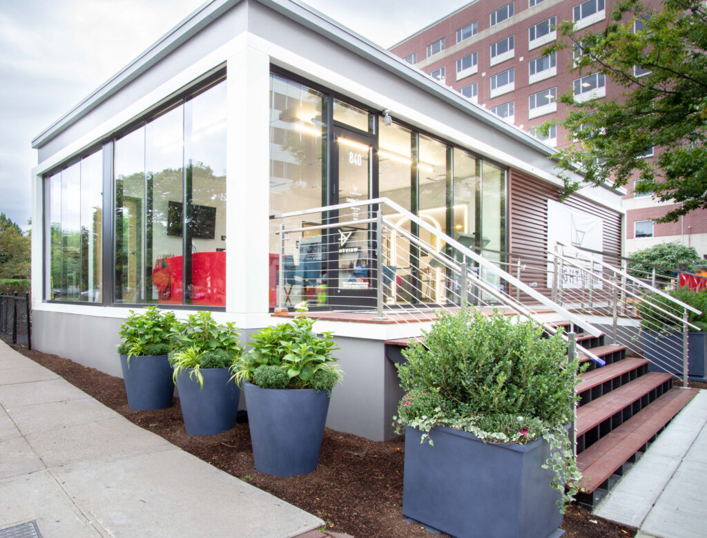 Modern triumph modular building featuring large glass windows and stylish landscaping, showcasing the benefits of modular construction for both permanent and temporary modular buildings.