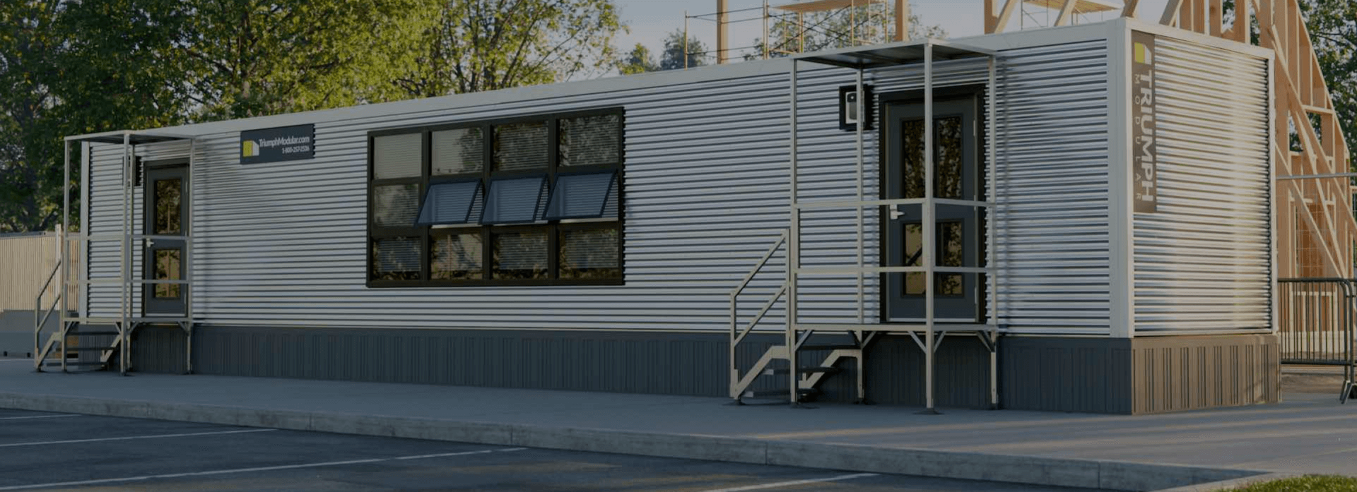 Exterior view of a triumph modular building featuring large windows and a staircase, showcasing modern modular construction design for temporary or permanent modular building solutions.