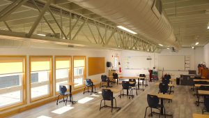 Interior of a modular classroom featuring desks and chairs, showcasing the benefits of triumph modular design in modular construction for educational spaces.