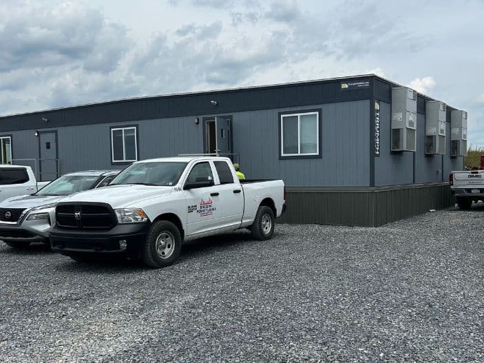 Modular office space with pickup trucks in front of it.