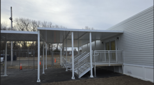 Side view of school entrance with stairs and covered walkway.