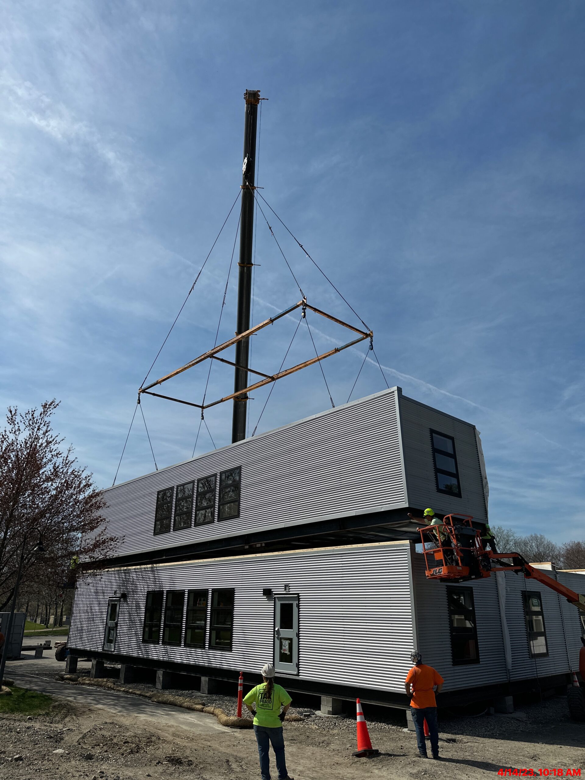 modular building being installed on construction site with a crane and workers