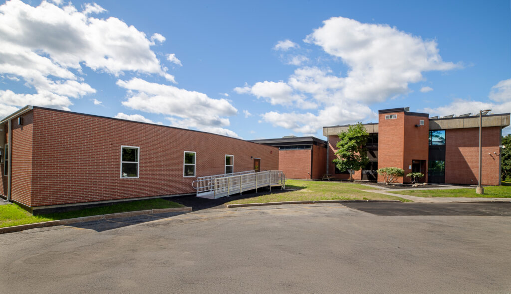 Image of front entrance of the modular classroom addition to Nashoba Valley Technical high school with existing school in the background.